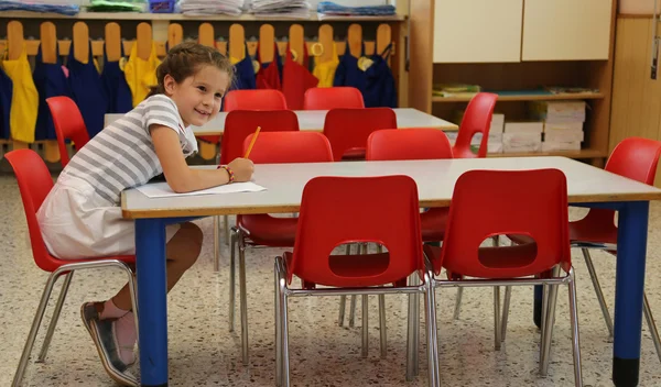 Lächelndes Mädchen schreibt auf Schulbank — Stockfoto