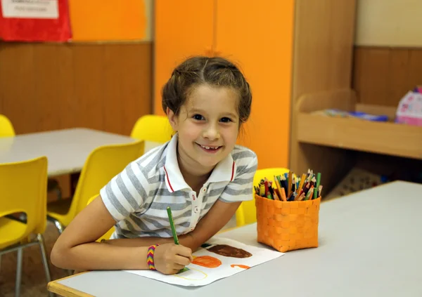 Bonita niña mientras dibuja con los colores del lápiz en scho — Foto de Stock