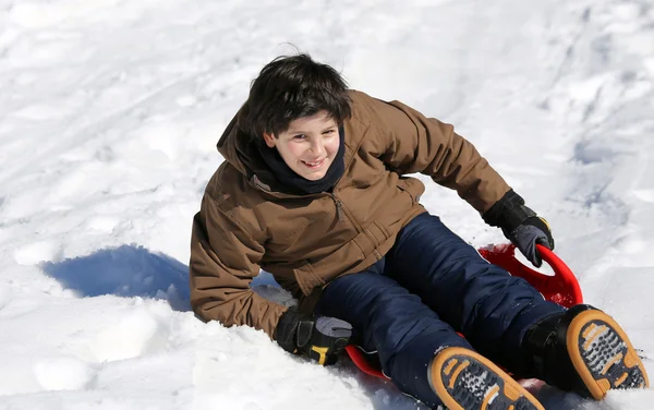 Niño disfrutando de trineo en la nieve en las montañas en invierno —  Fotos de Stock