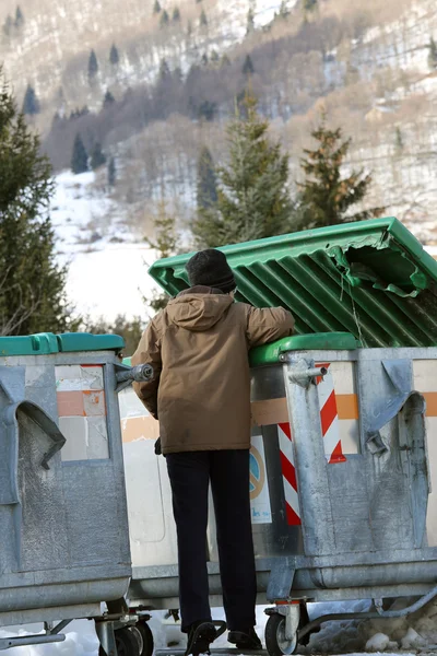 Pauvre garçon essaie de manger dans la boîte à déchets en hiver — Photo
