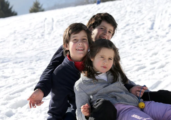 Tres hermanos sonrientes sobre el trineo en invierno en las montañas —  Fotos de Stock