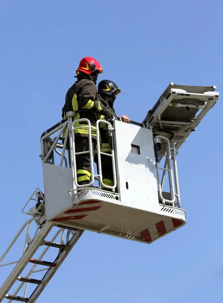 Two firefighters in the cage of fire engine — Stock Photo, Image