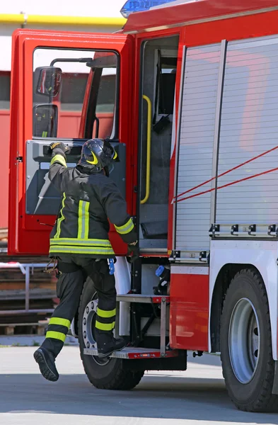 Firefighter in action jump down quickly from the fire truck — 图库照片