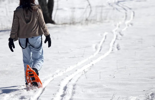 Junge Frau mit zwei orangefarbenen Schneeschuhen in den Bergen — Stockfoto