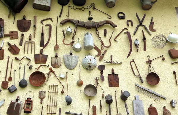 Many ancient farming tools hanging on the wall — Stock Photo, Image