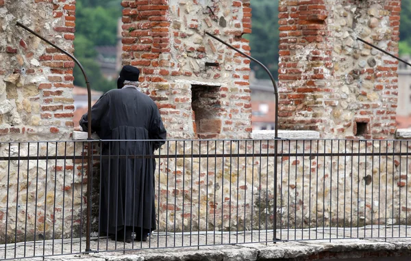 Viejo sacerdote mira en la pared del castillo —  Fotos de Stock