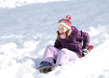 girl laughs while slips with tobogganing in winter