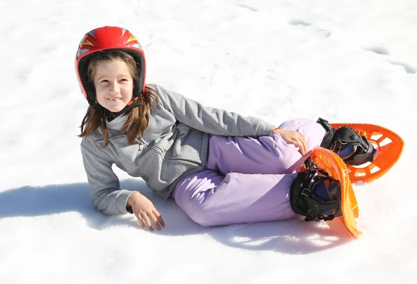 Pretty girl with orange snowshoes on snow in winter — Stockfoto