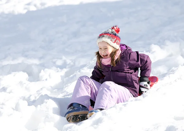 Girl laughs while slips with tobogganing in winter — Stockfoto