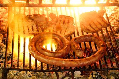 sausage and pork chop in the fireplace with the glowing embers