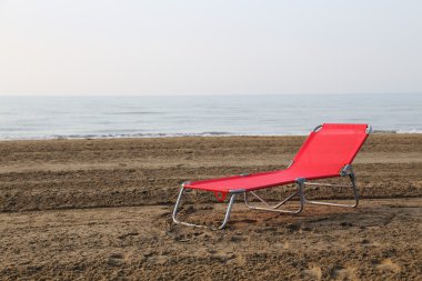 Yaz aylarında kumsalda deniz s ortasında kırmızı sunlounger