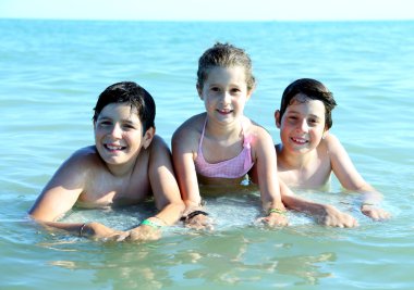 Üç genç kardeş denizde yaz aylarında oynarken iyi eğlenceler