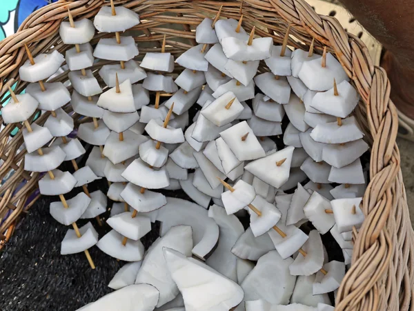 Leckere Fruchtspieße mit Kokosnussstücken zum Verkauf am Strand — Stockfoto