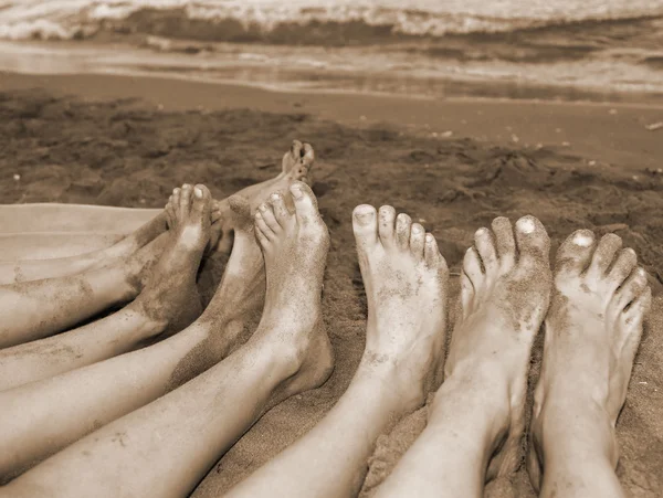 Voeten van een gezin door de zee op het strand — Stockfoto