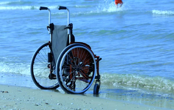 Silla de ruedas roja en la playa de arena en verano — Foto de Stock