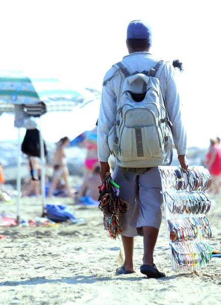 Vendedor de óculos de sol e colares na praia no verão — Fotografia de Stock