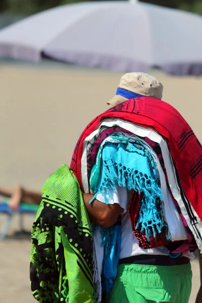 African peddler of fabrics and Slipcovers on the beach — Stock Photo, Image