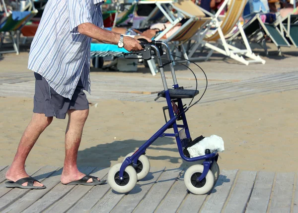 Äldre man promenerar med Walker på stranden på sommaren — Stockfoto