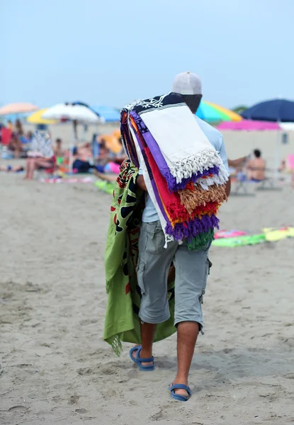 Peddler of colorful towels by the sea on the beach — Stock Photo, Image
