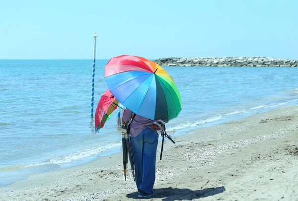 Handlarz z kolorowych parasoli nad morzem na plaży latem — Zdjęcie stockowe