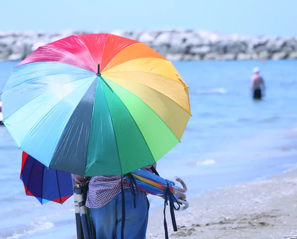 Anciano de coloridas sombrillas junto al mar en la playa — Foto de Stock