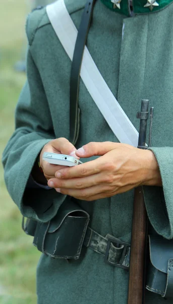 Gewehr und Smartphone eines Soldaten während der Nachstellung einer Schlacht — Stockfoto