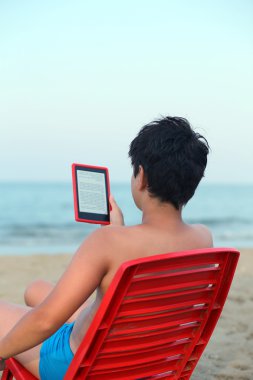 Çocuk deniz kıyısında ebook okur