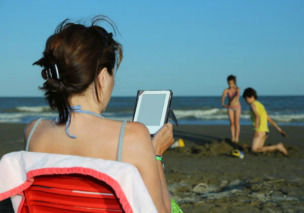 Femme lit l'ebook sur la plage en été — Photo