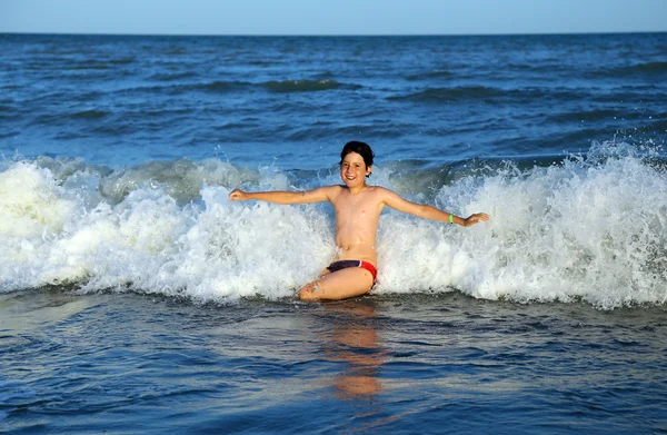 Kid gör stänkvatten i vågor i havet på sommaren — Stockfoto