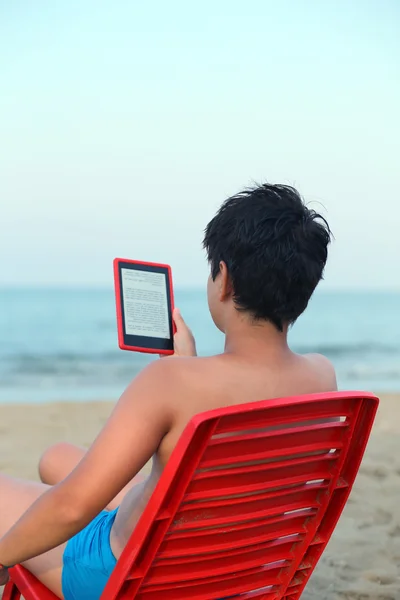 海の海岸上の電子ブックを読む少年 — ストック写真