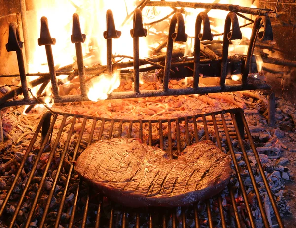 beef steak cooked on the barbeque fireplace with flame