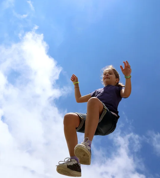 Cheerful little girl makes a big jump and blue sky in summer — Stock Photo, Image