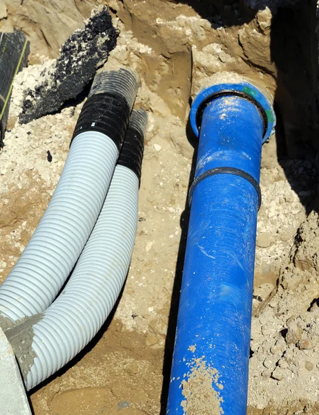 Rohre und ein Rohr für Wasserwerke beim Graben im Straßenbau — Stockfoto