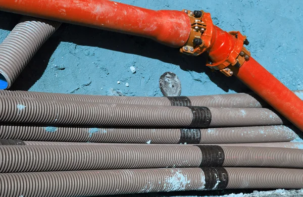 Corrugated pipes and a red pipe in digging in the road construct — Stock Image Corrugated pipes and a red pipe in digging in the road construct Stock Image