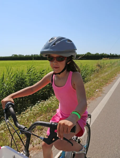 Menina de oito anos vai de bicicleta com capacete — Fotografia de Stock