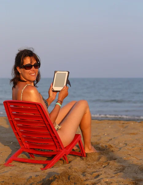 Piękna kobieta w strój kąpielowy czyta ebook na plaży — Zdjęcie stockowe