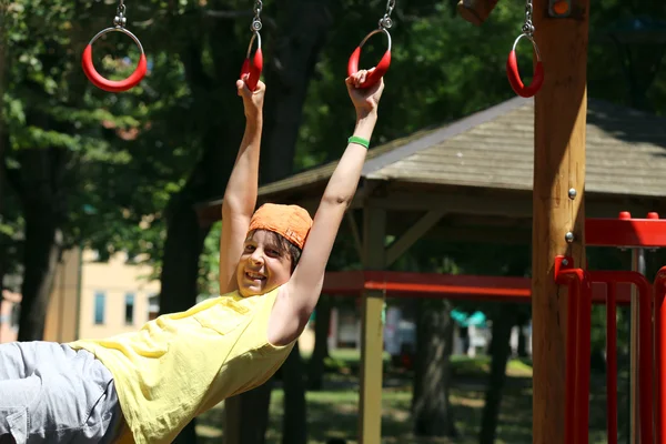 Bambino gioca con anelli di parco giochi all'aperto — Foto Stock