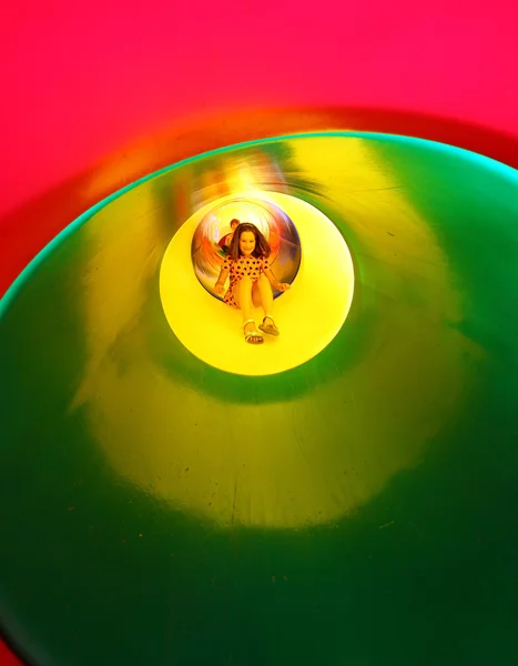 Little girl on the playground in a colorful tunnel slide — Stock Photo, Image