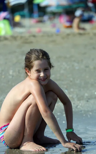 Jeune fille en maillot de bain accroupi sur la plage — Photo