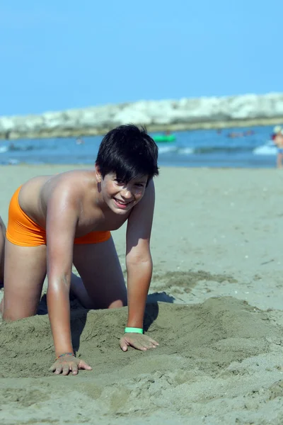 Ung pojke på stranden leker med sand — Stockfoto
