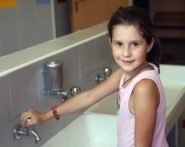 Little girl is washing her hands in the sink in the bathroom of — Stock Photo, Image