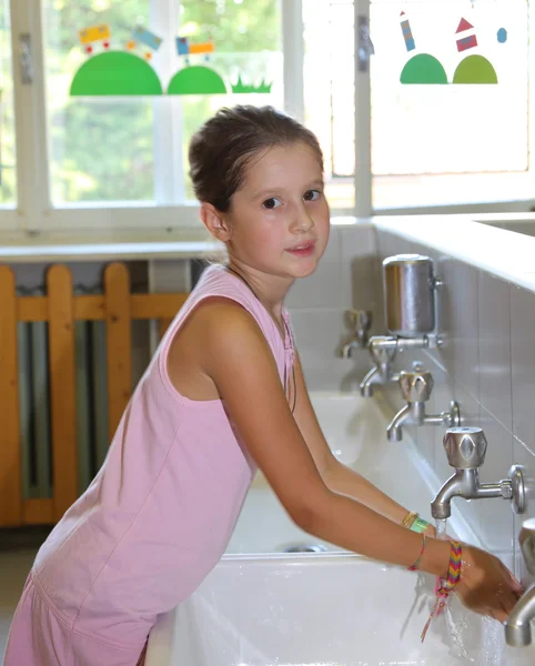 little girl washing hands in the ceramic sink in the bathroom