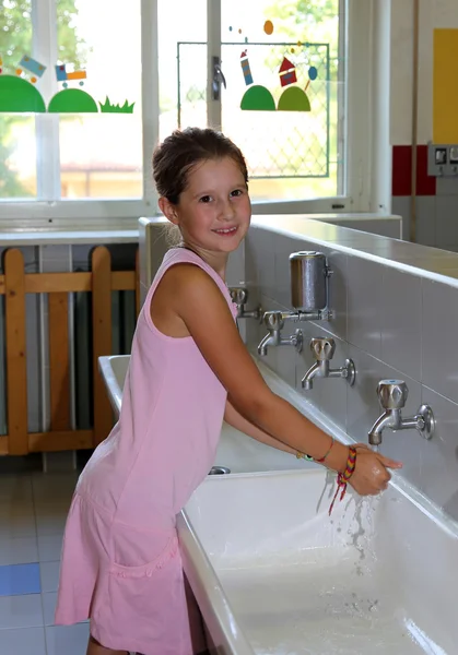 Menina lavar as mãos na pia de cerâmica no banheiro o — Fotografia de Stock