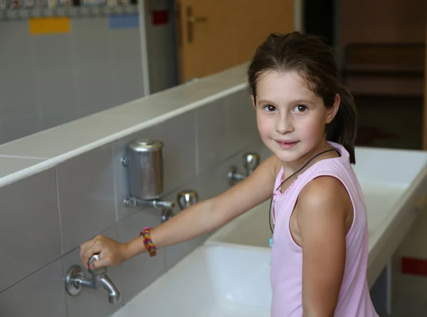 Bonita niña lavándose las manos en el fregadero de cerámica en el baño —  Fotos de Stock