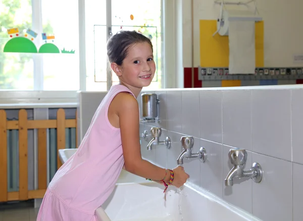 Niña lavándose las manos en el lavabo de cerámica en el baño o — Foto de Stock