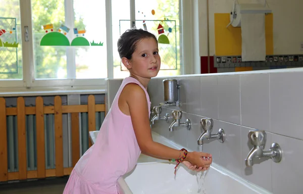 Niña lavándose las manos en el lavabo de cerámica en el baño o — Foto de Stock