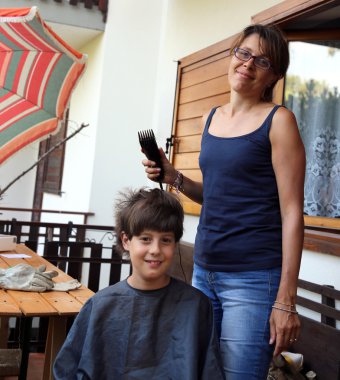 Genç anne oğlunun saç ustura ile keser.