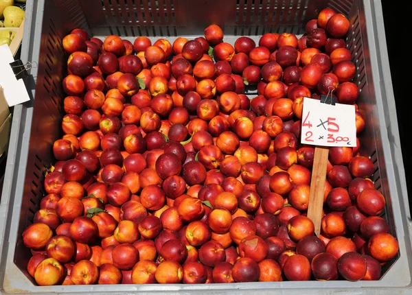Gran caja de nectarinas de melocotón maduras para la venta en el mercado de verduras —  Fotos de Stock