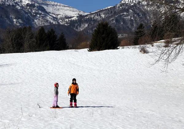 Двое детей в шлеме и снегоступах в горы — стоковое фото