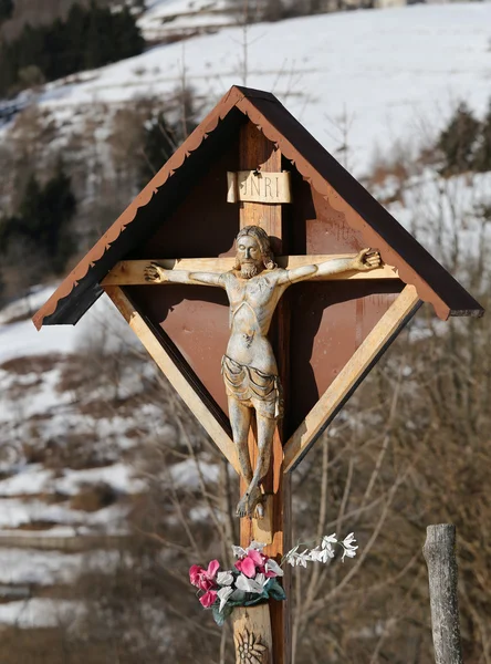 Crucifixo de madeira com capitelo em um distrito de um vilão de montanha — Fotografia de Stock